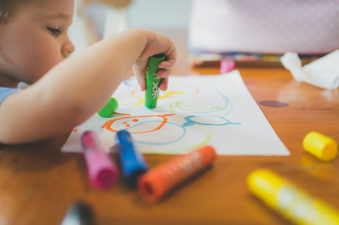 Young child sitting at a table drawing with crayons