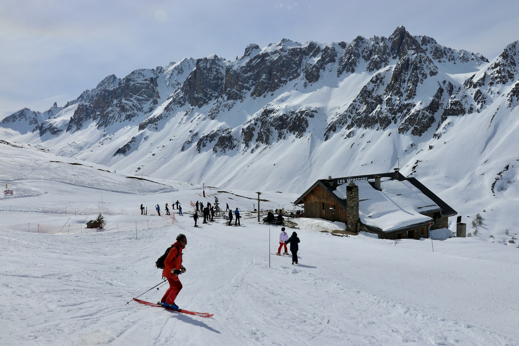Skiers on a sunny French Alps slope with snow-covered mountain peaks
