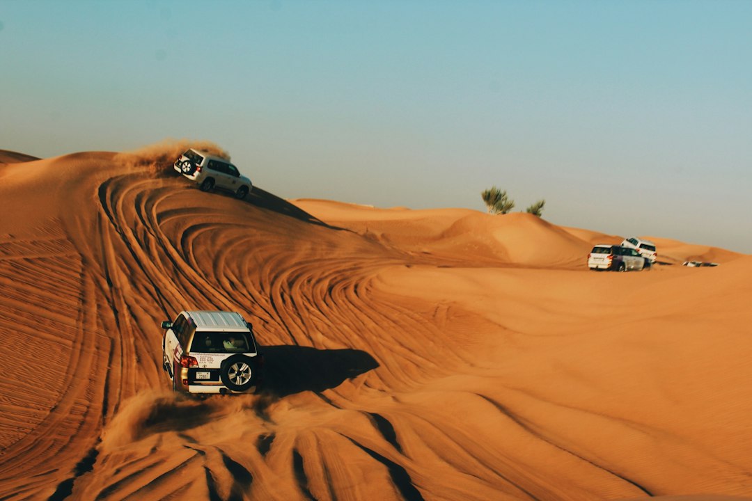 Desert safari vehicles crossing golden sand dunes near Dubai