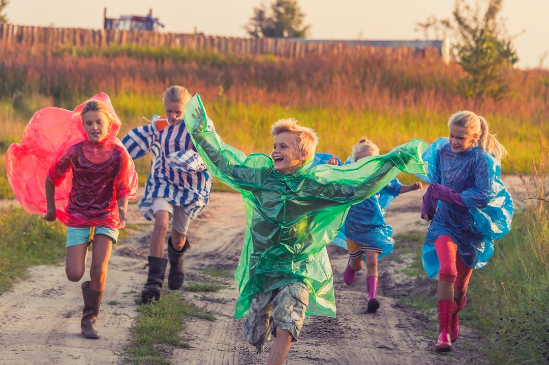 Children in colorful raincoats running and laughing outdoors