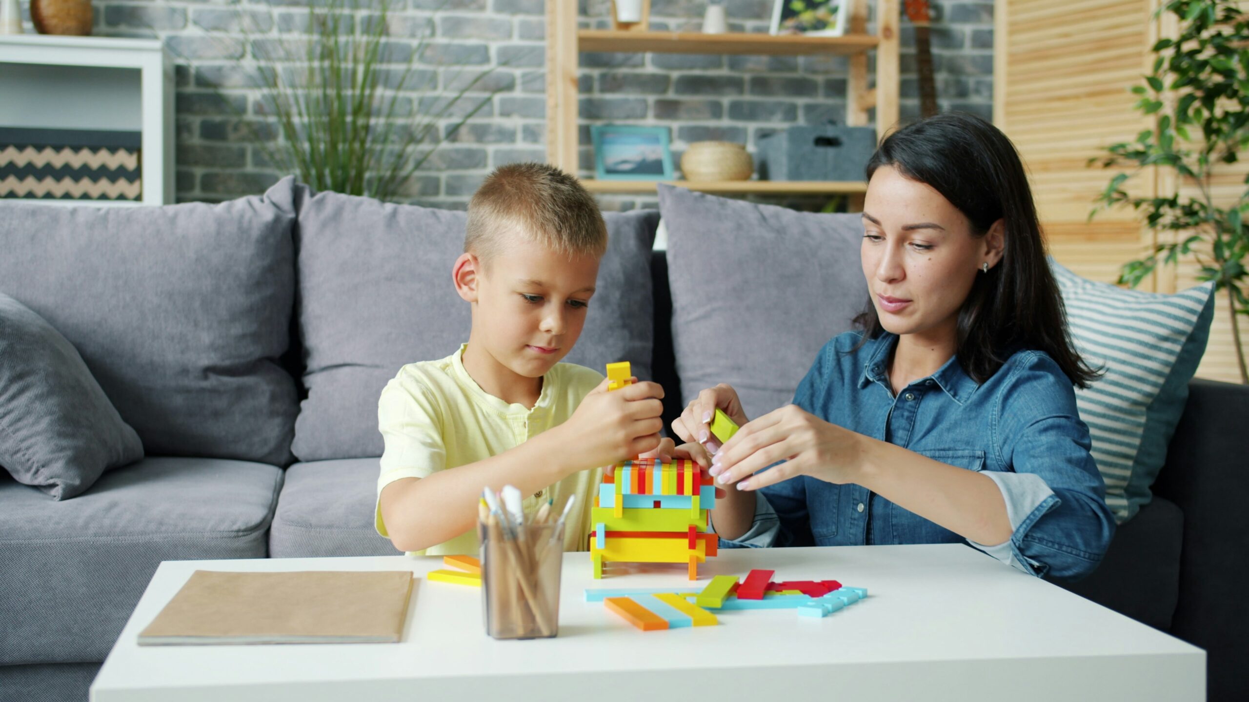 Parent helping a toddler build with blocks during play