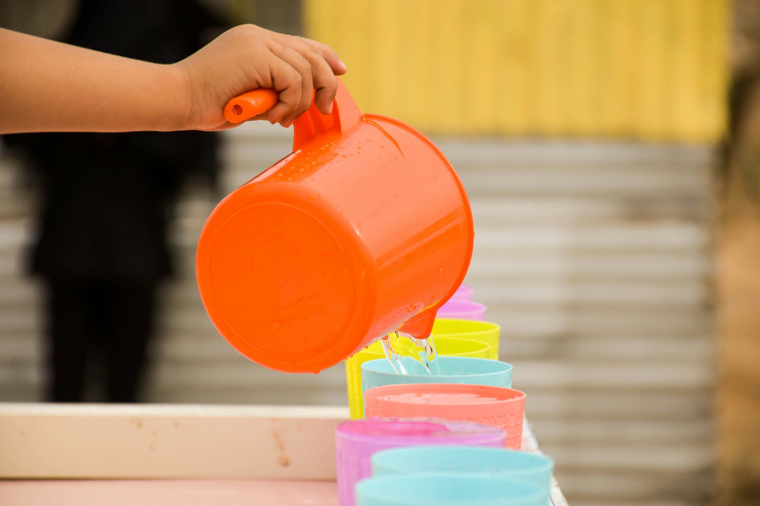 Hands pouring water into a cup during a simple practical-life activity